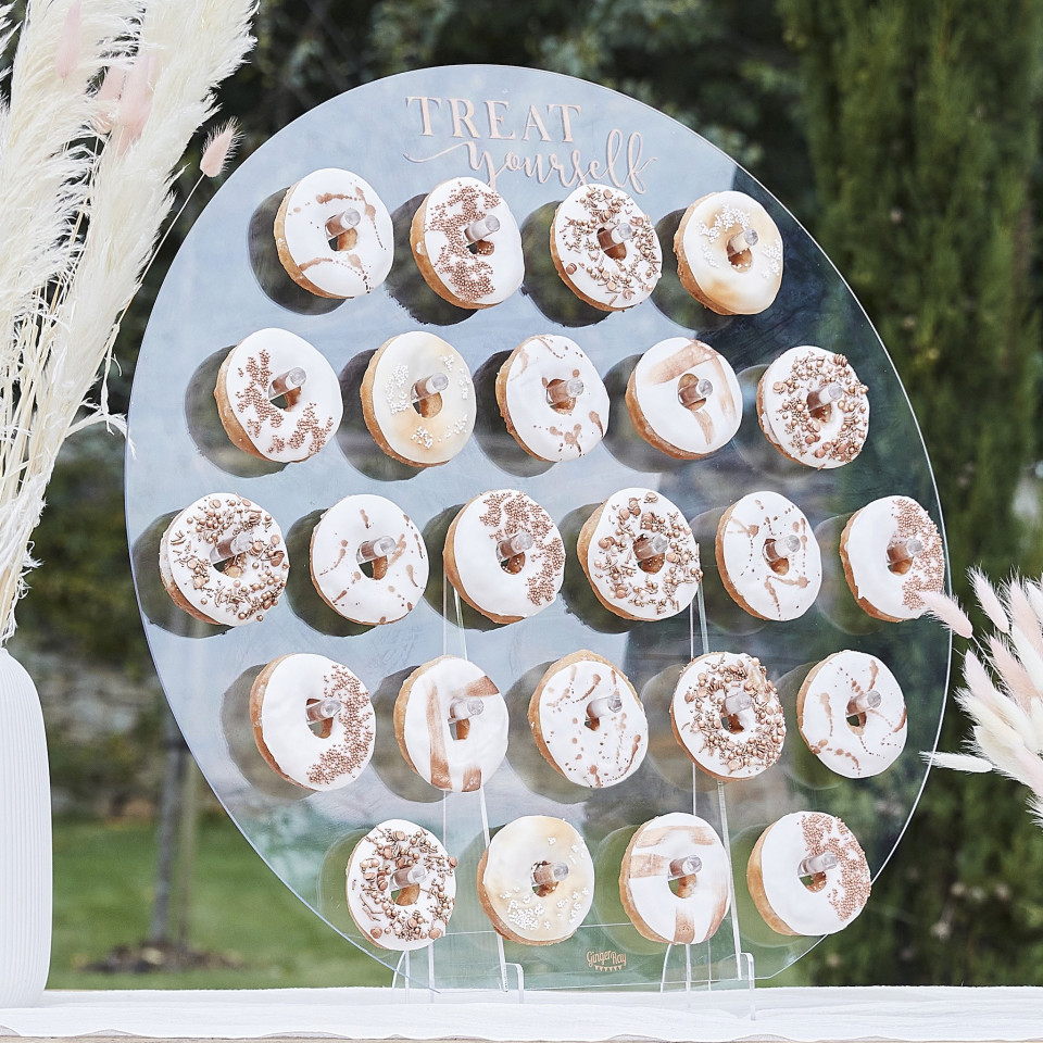 een bruiloftsreceptietafel met donuts en een glazen display