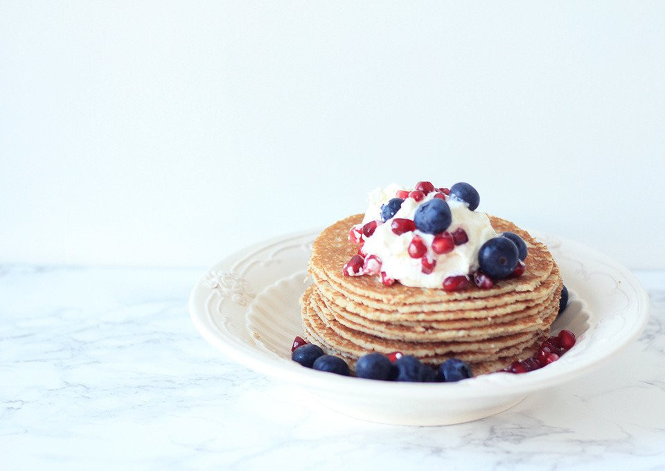 pannenkoeken met bosbessen en room op een wit bord