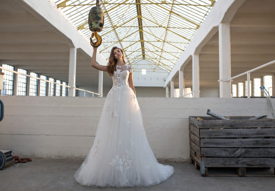 een vrouw in een trouwjurk die in een leeg magazijn staat