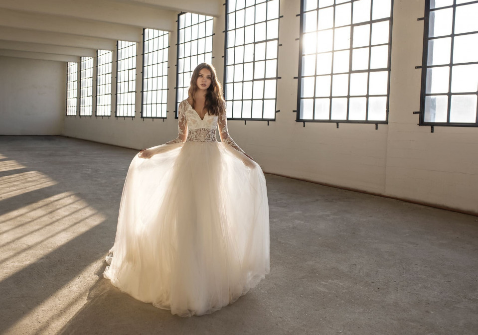 een vrouw in een trouwjurk die in een lege kamer staat