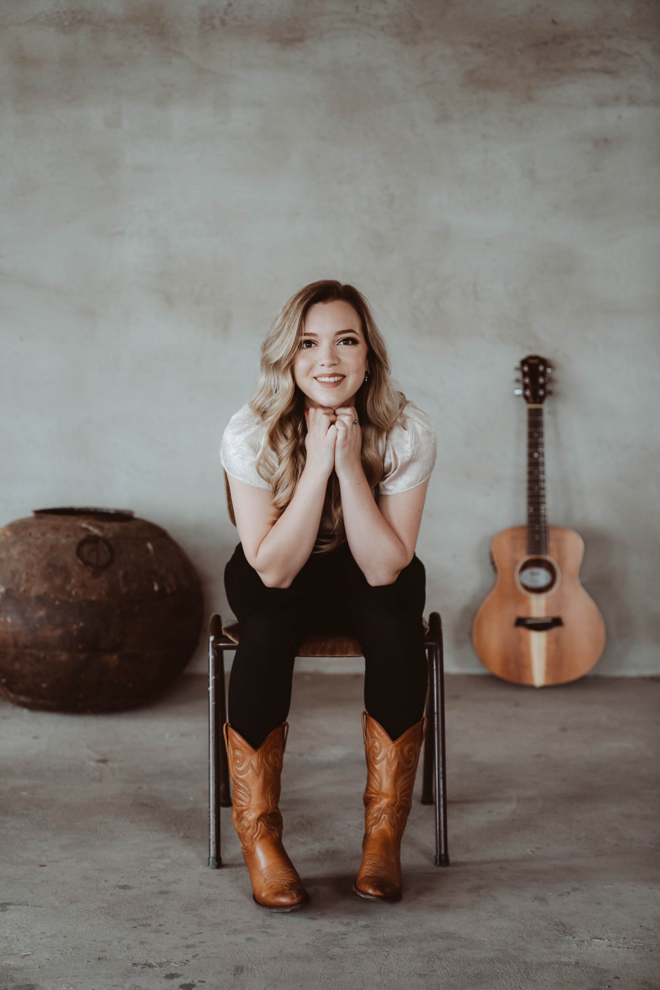 een vrouw die op een stoel zit met een gitaar en laarzen