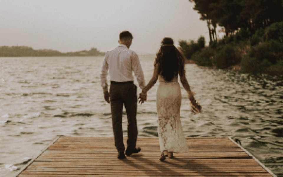een bruid en bruidegom wandelen op een steiger bij het water