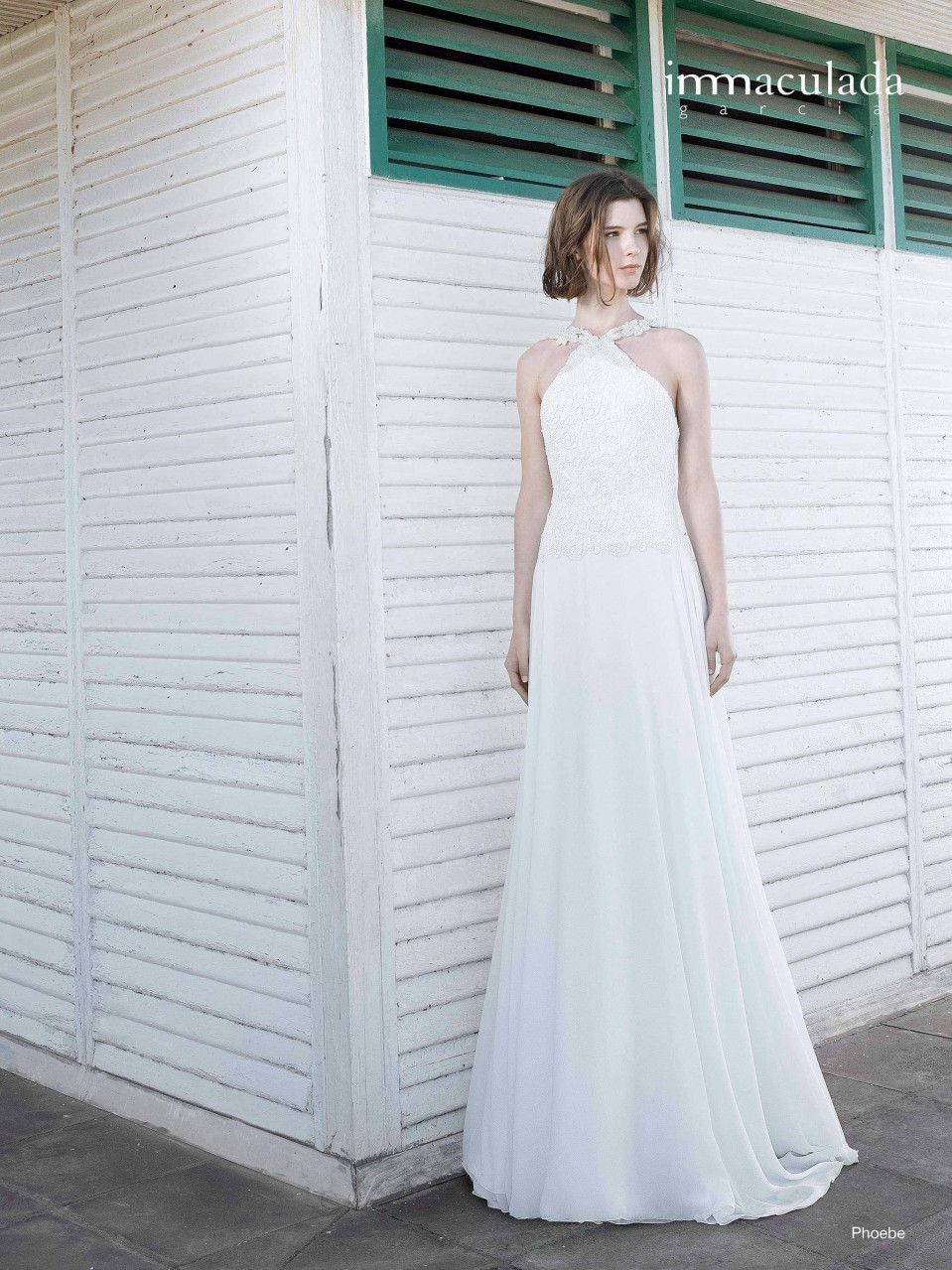 een vrouw in een witte trouwjurk staande bij een muur