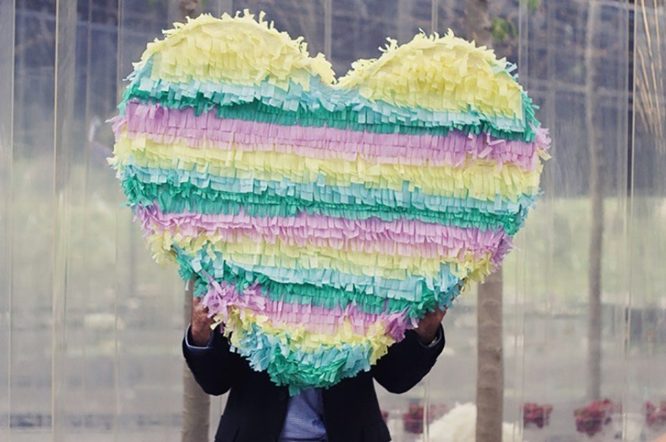 een man die een grote piñata met een hartvorm vasthoudt