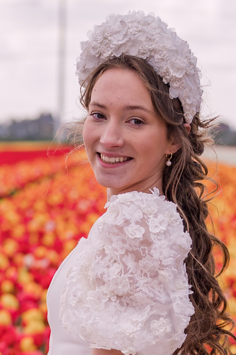 een jonge vrouw in een witte jurk die staat in een veld van tulpen