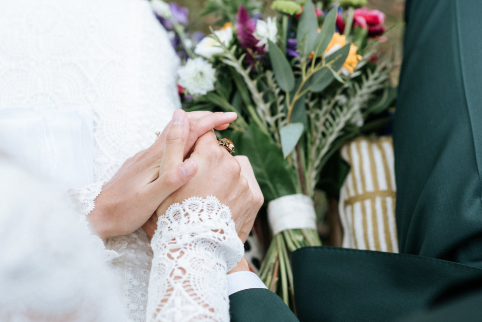 bruidspaar dat elkaars handen vasthoudt en trouwringen vasthoudt