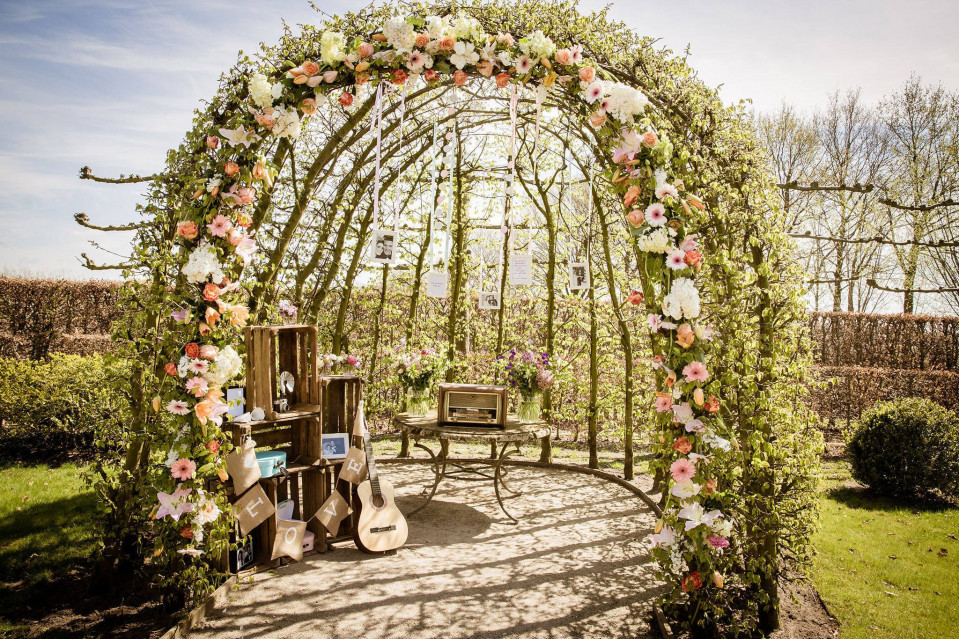 een huwelijksboog versierd met bloemen en een gitaar