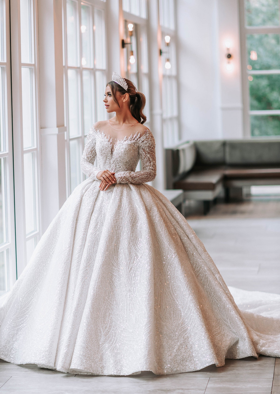 een bruid in een trouwjurk die poseert voor een grote raam