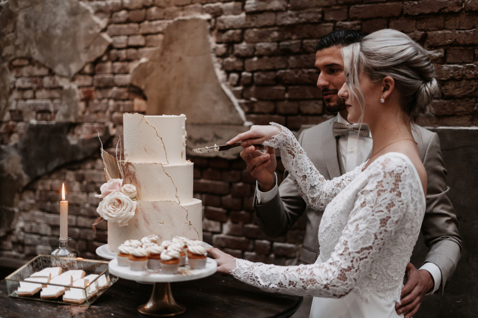bruid en bruidegom snijden taart aan tijdens bruiloftsreceptie