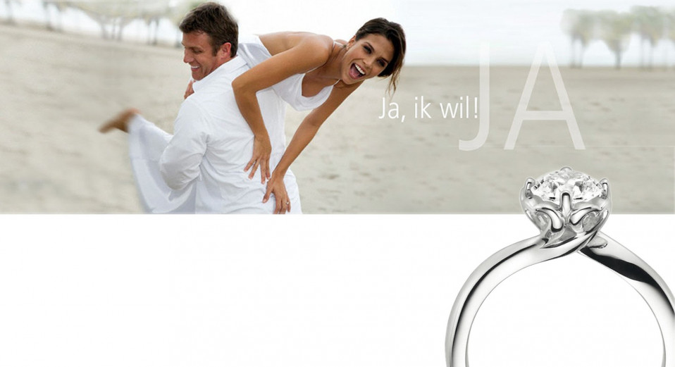 een man en vrouw staan op het strand met een ring