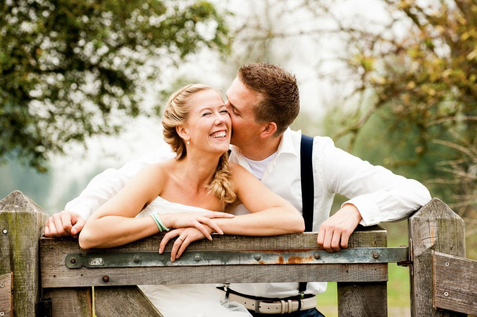 een bruid en bruidegom leunen tegen een hek