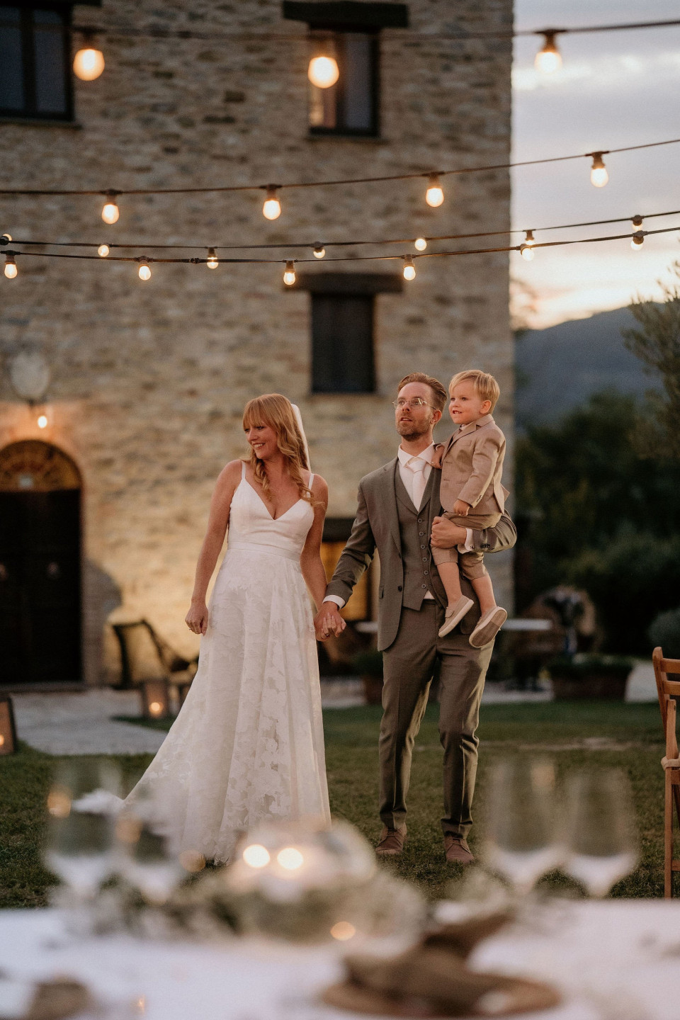 de bruid en bruidegom die de hand van hun zoon vasthouden terwijl ze het gangpad aflopen