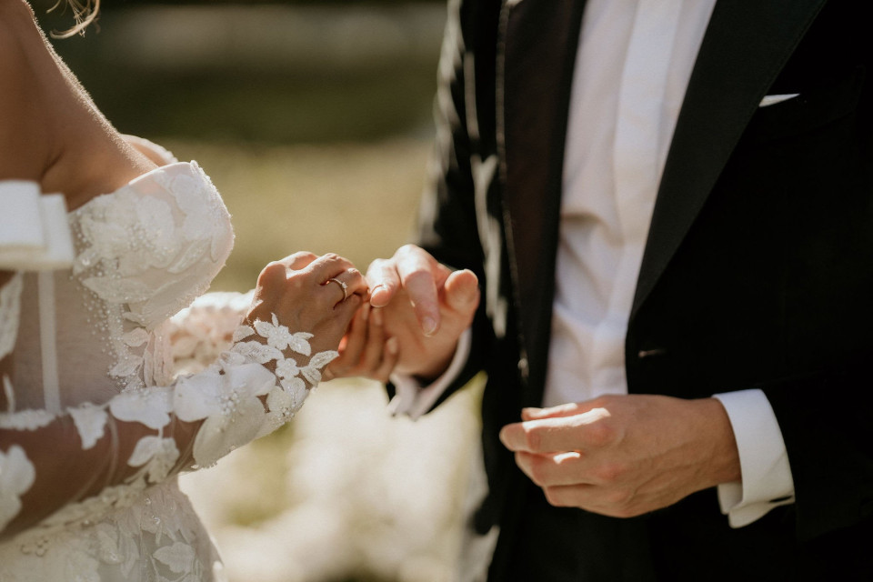 een close-up van een bruid en bruidegom die elkaars hand vasthouden