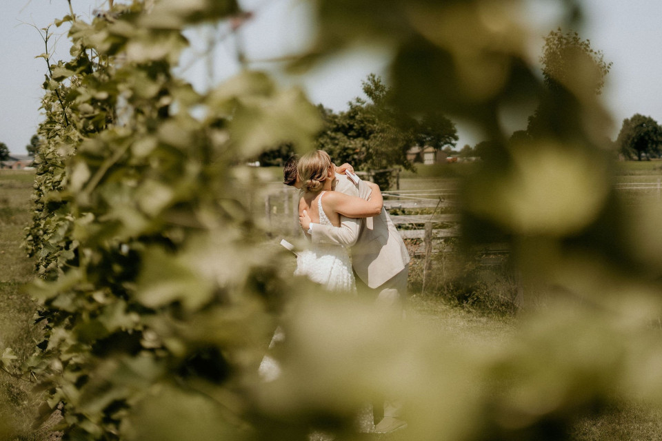 een bruid en bruidegom die in een veld kussen
