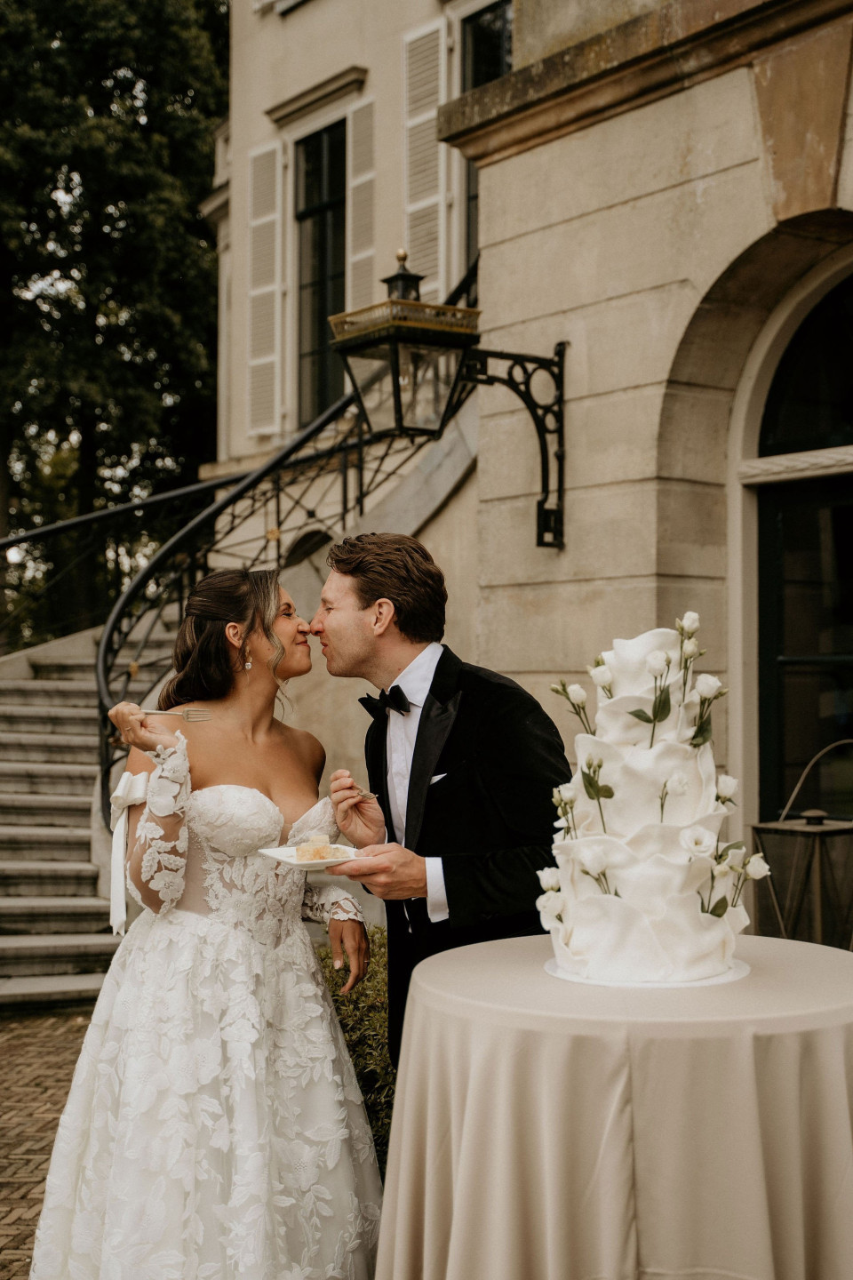 een bruid en bruidegom die voor een bruidstaart kussen