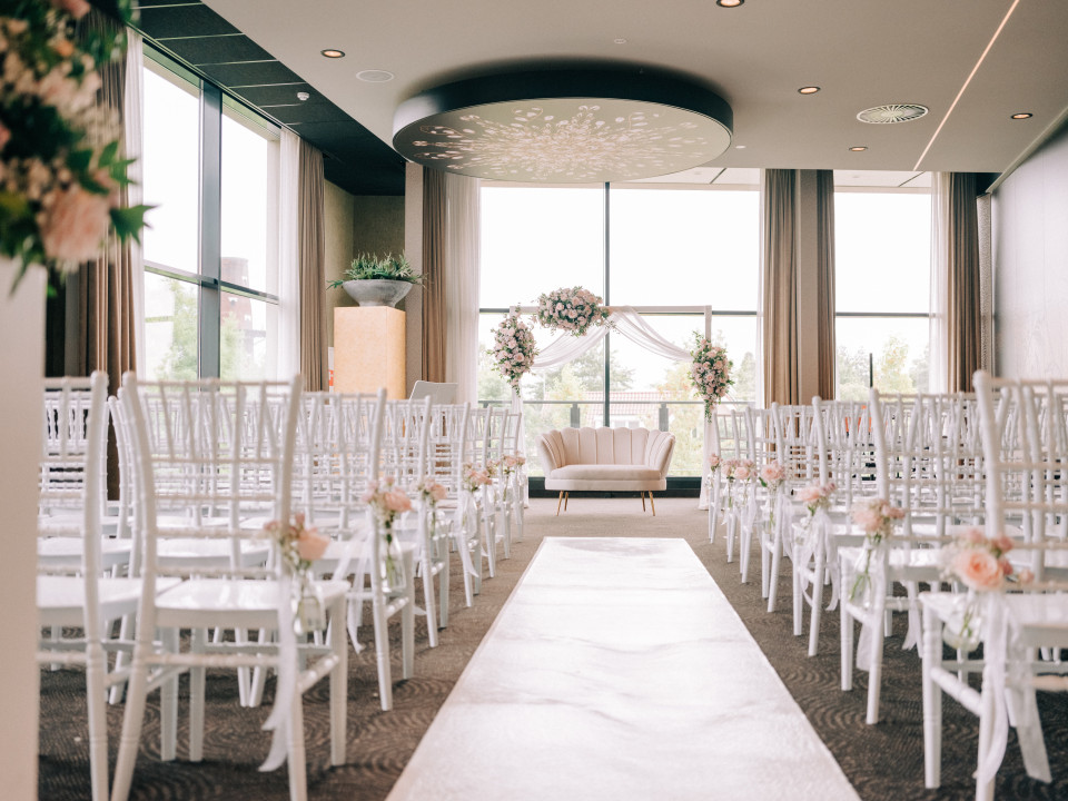 een trouwceremonie met witte stoelen en bloemen