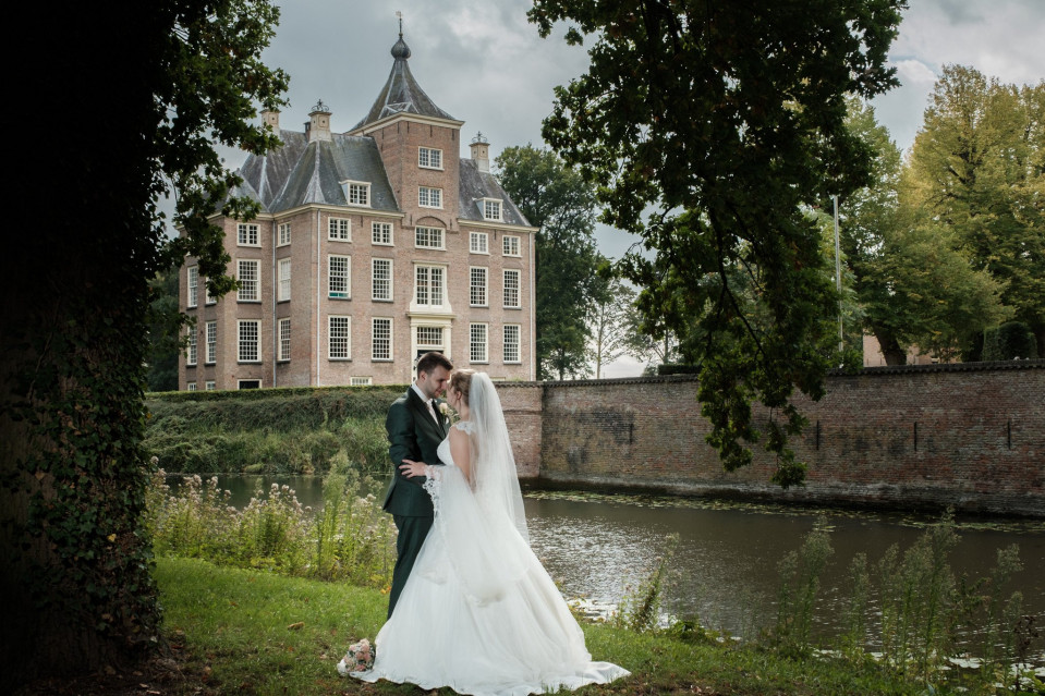 een bruid en bruidegom poseren voor een kasteel