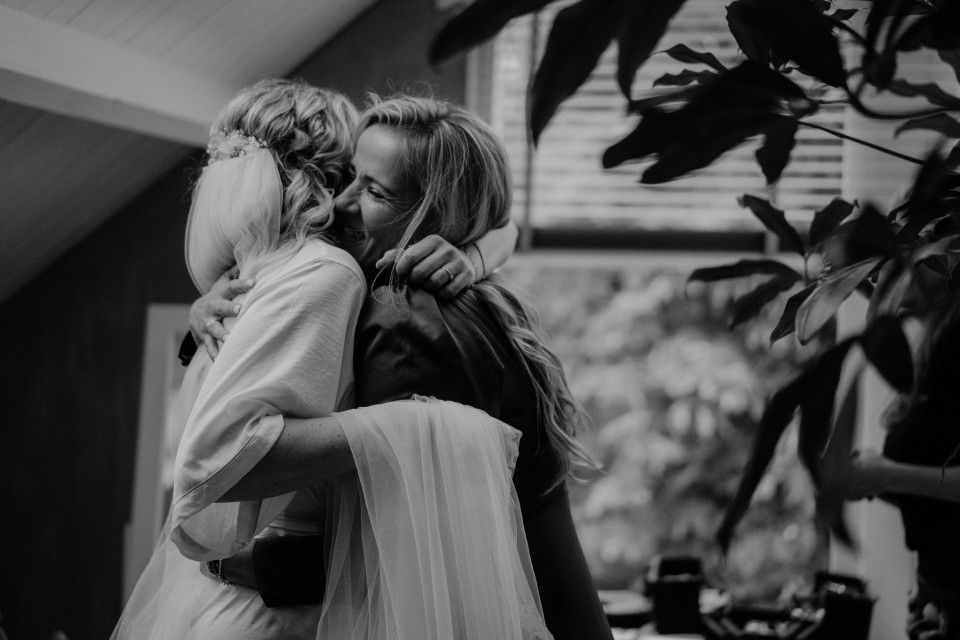 een bruid omhelst haar moeder terwijl ze zich voorbereiden op hun bruiloft