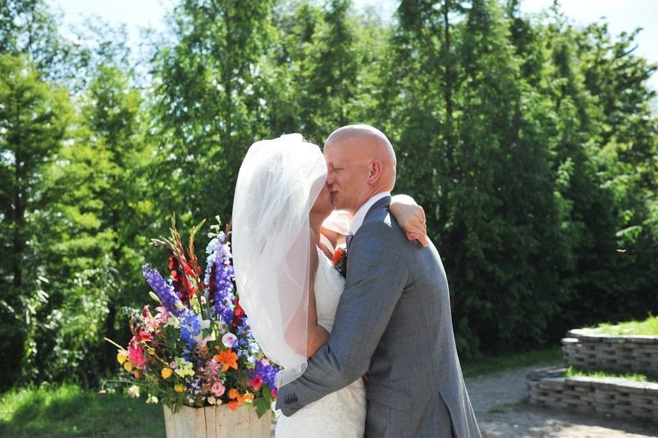 een bruid en bruidegom kussen voor een bloemstuk