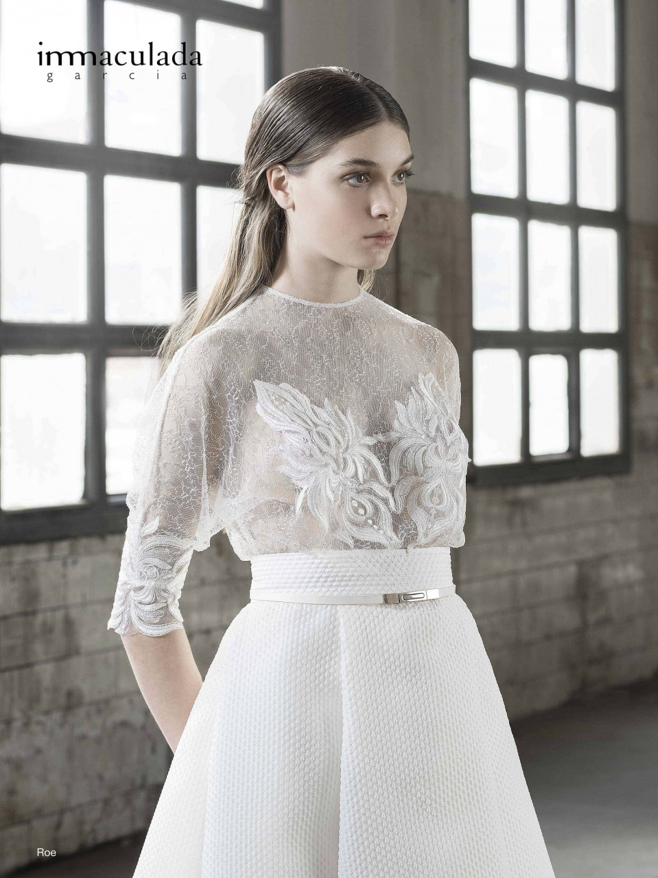 het model draagt een witte jurk met doorschijnende mouwen