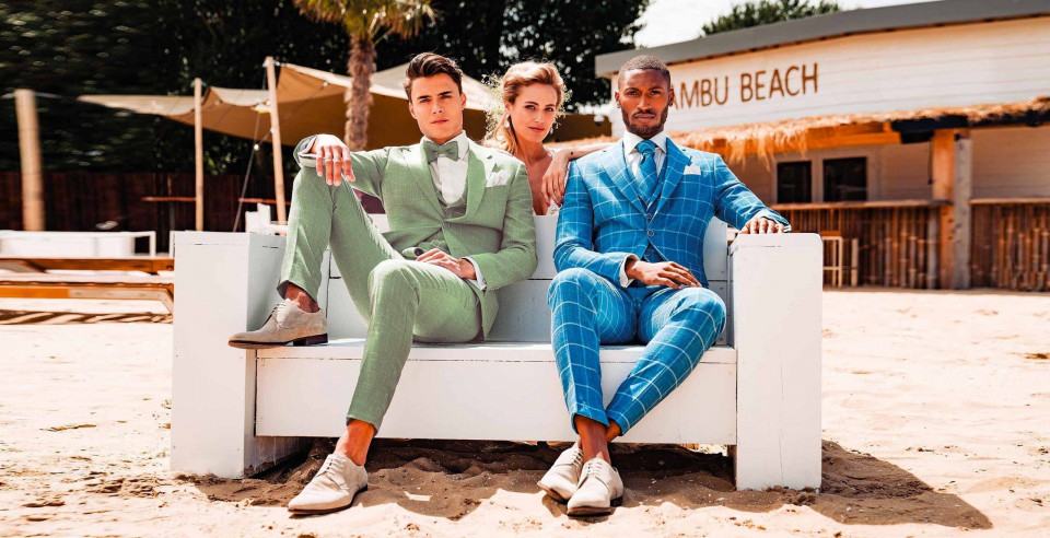 drie mensen in pakken die op een bank op het strand zitten