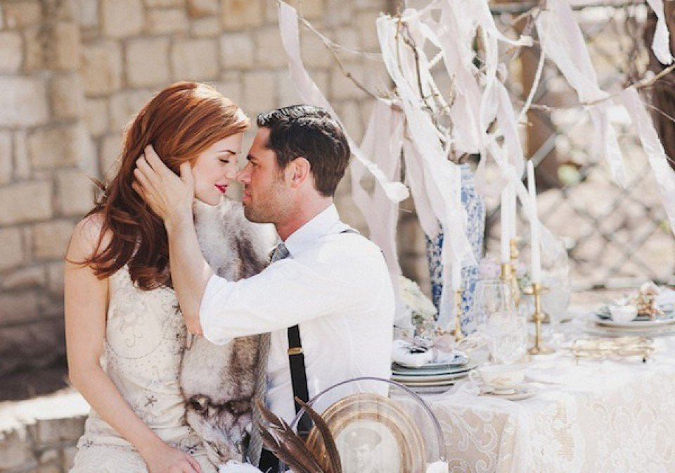 een bruid en bruidegom zitten aan een tafel met een wit tafelkleed