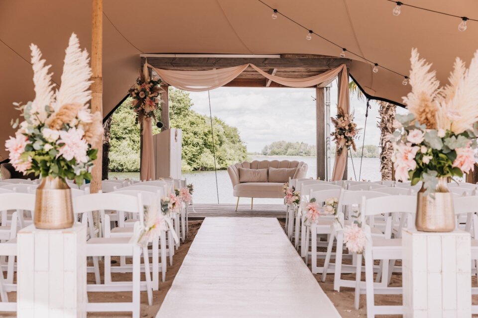 Trouwceremonie aan het water met roze styling