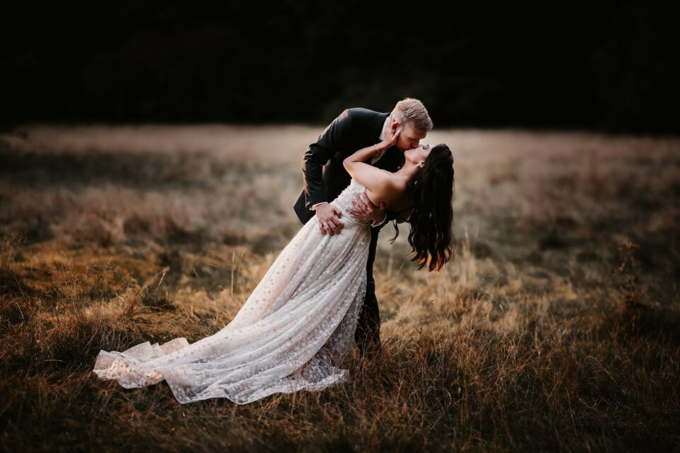 een afbeelding van een bruid en bruidegom die kussen in een veld