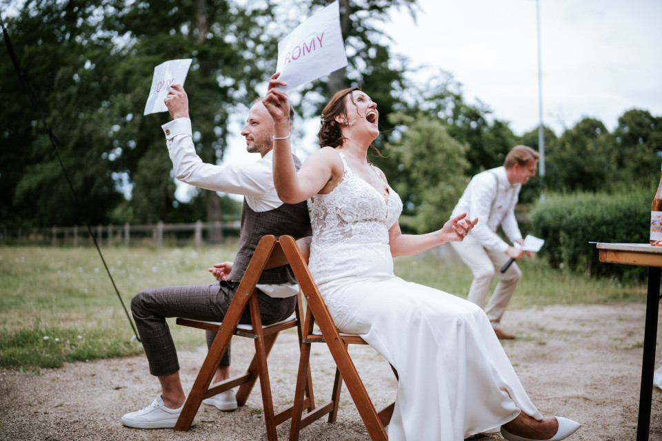 bruid en bruidegom zitten op stoelen met borden