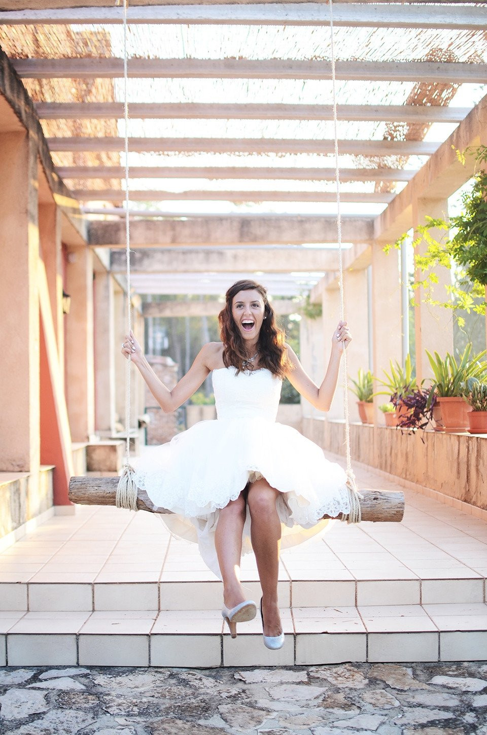 een bruid in een witte jurk zit op een schommel