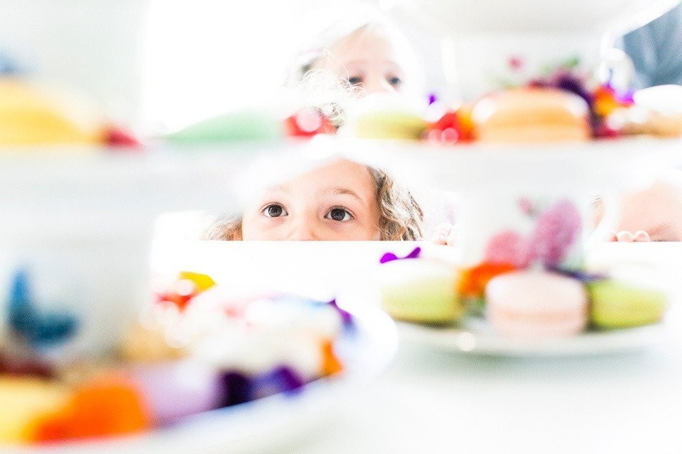 een klein meisje dat uitkijkt vanachter een bord met cupcakes