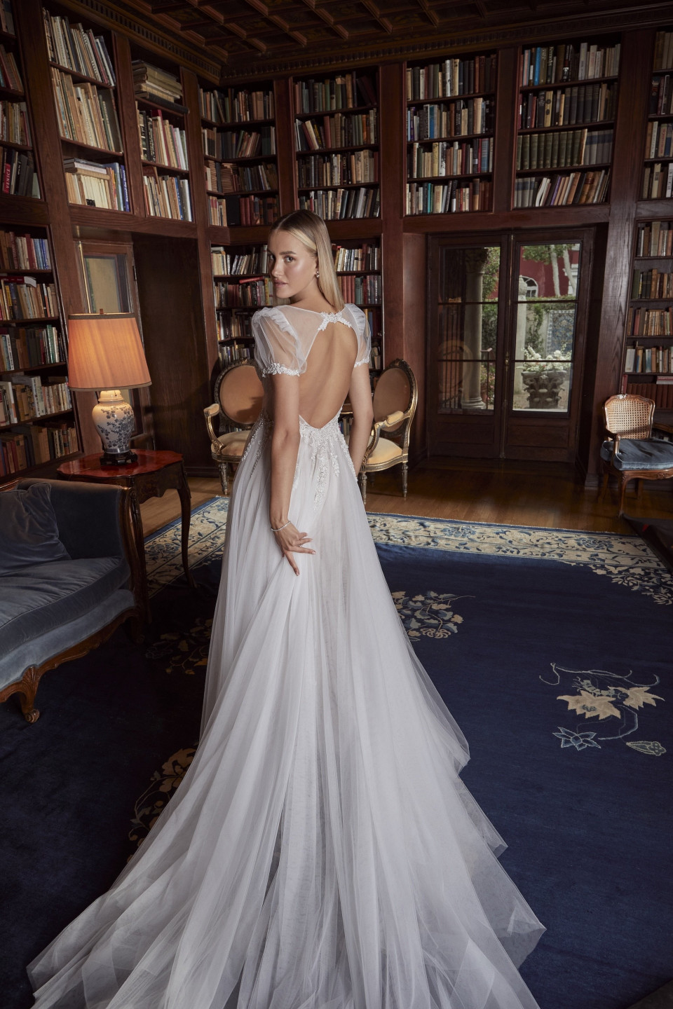 een vrouw in een trouwjurk die voor een bibliotheek staat