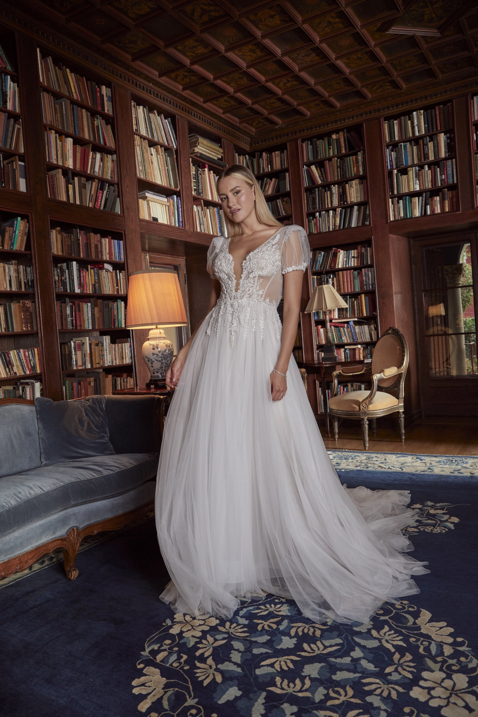 een vrouw in een trouwjurk die voor een boekenkast staat