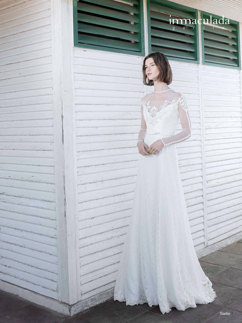 een vrouw in een trouwjurk staande bij een wit gebouw