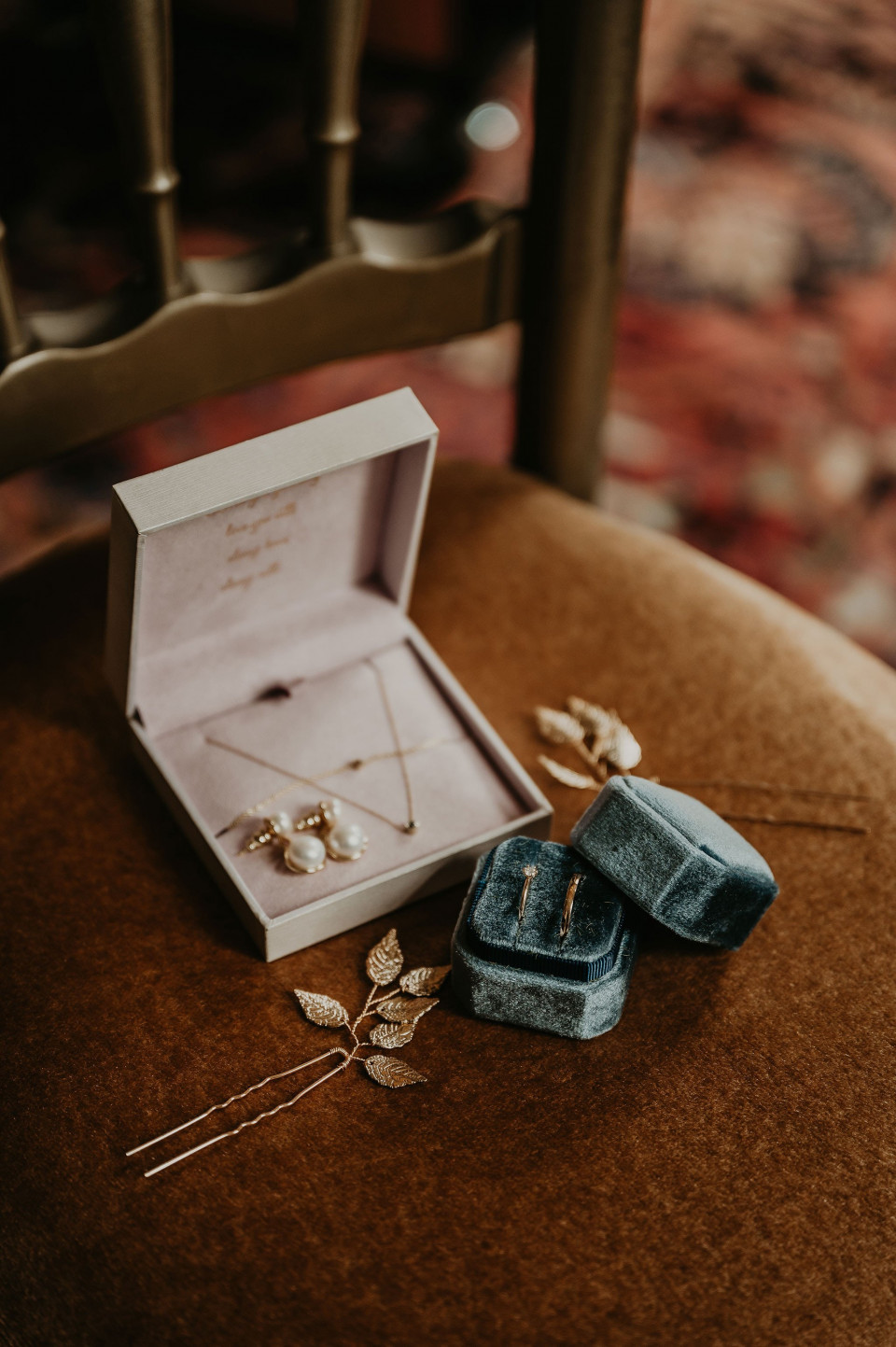 een paar oorbellen en een broche op een stoel