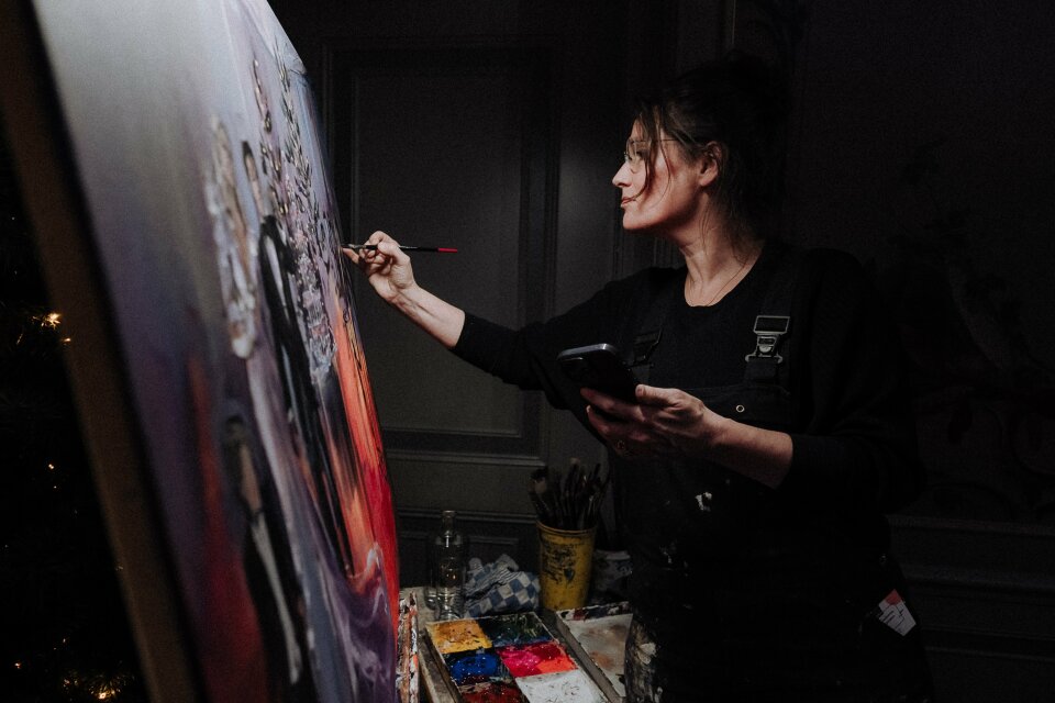 een vrouw die op een canvas schildert in een donkere kamer