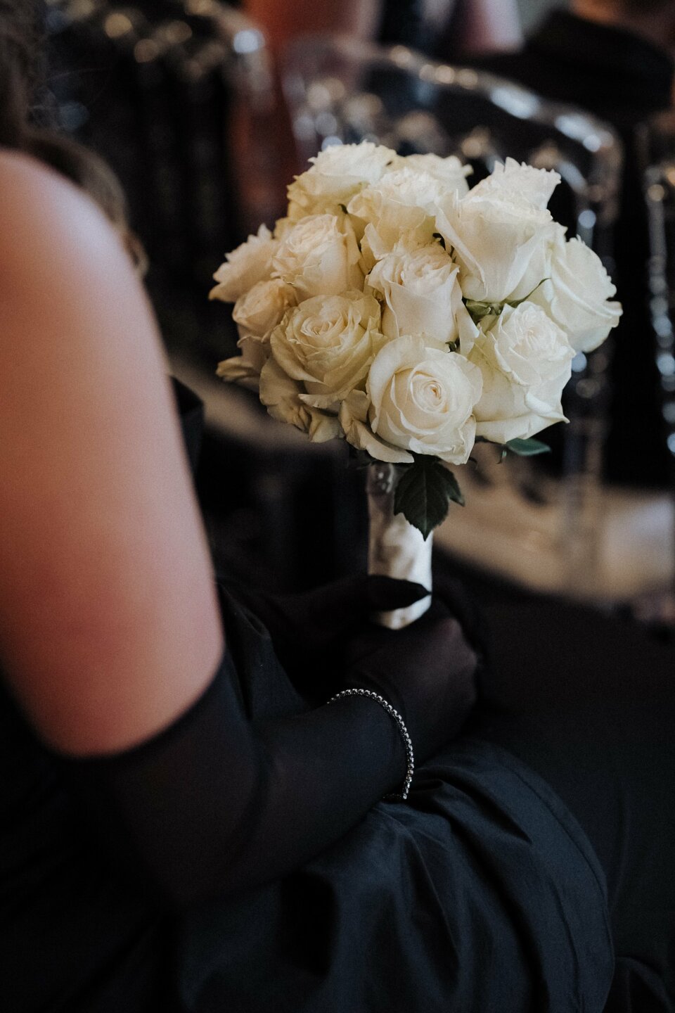 een vrouw in een zwarte jurk die een boeket witte rozen vasthoudt