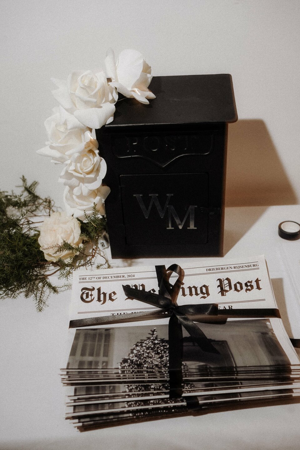 een zwarte brievenbus met een zwarte strik en een bos witte bloemen