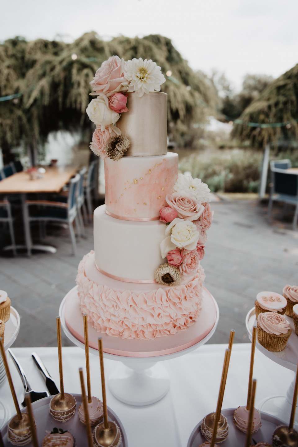 een bruidstaart met roze en gouden bloemen