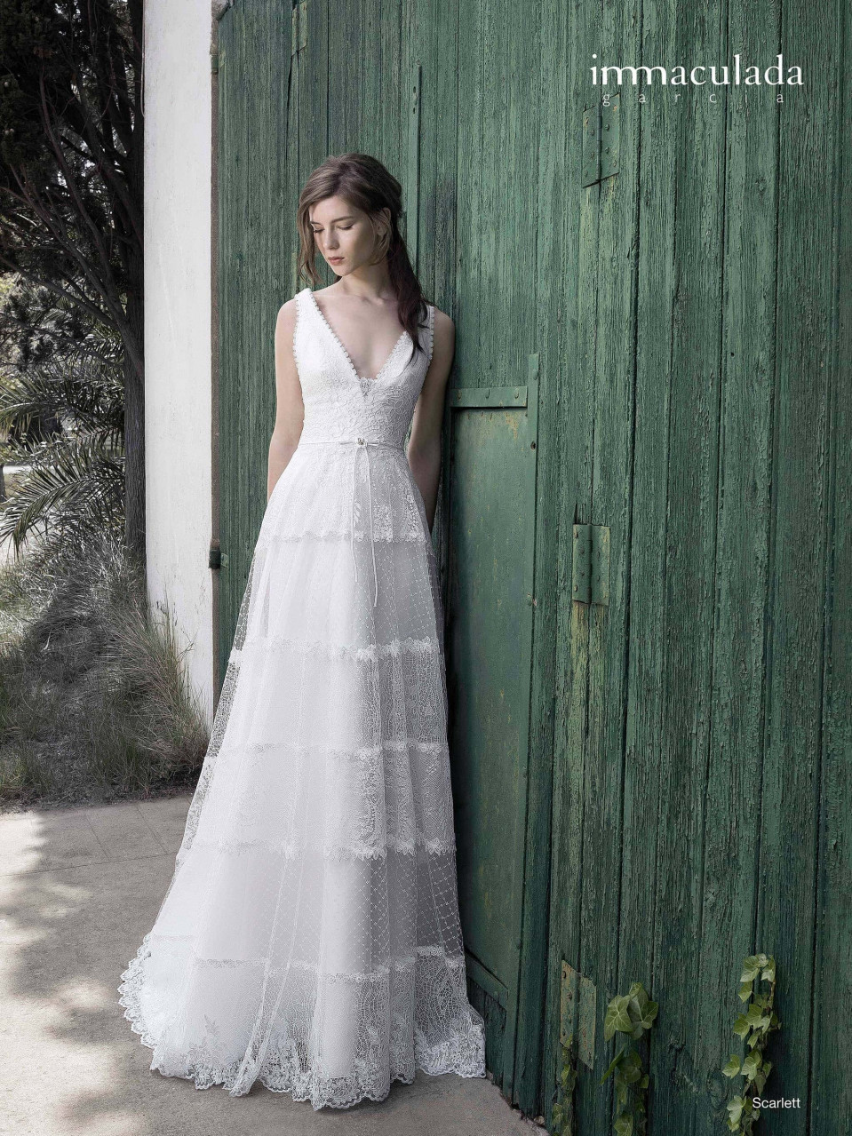 een vrouw in een trouwjurk leunend tegen een muur