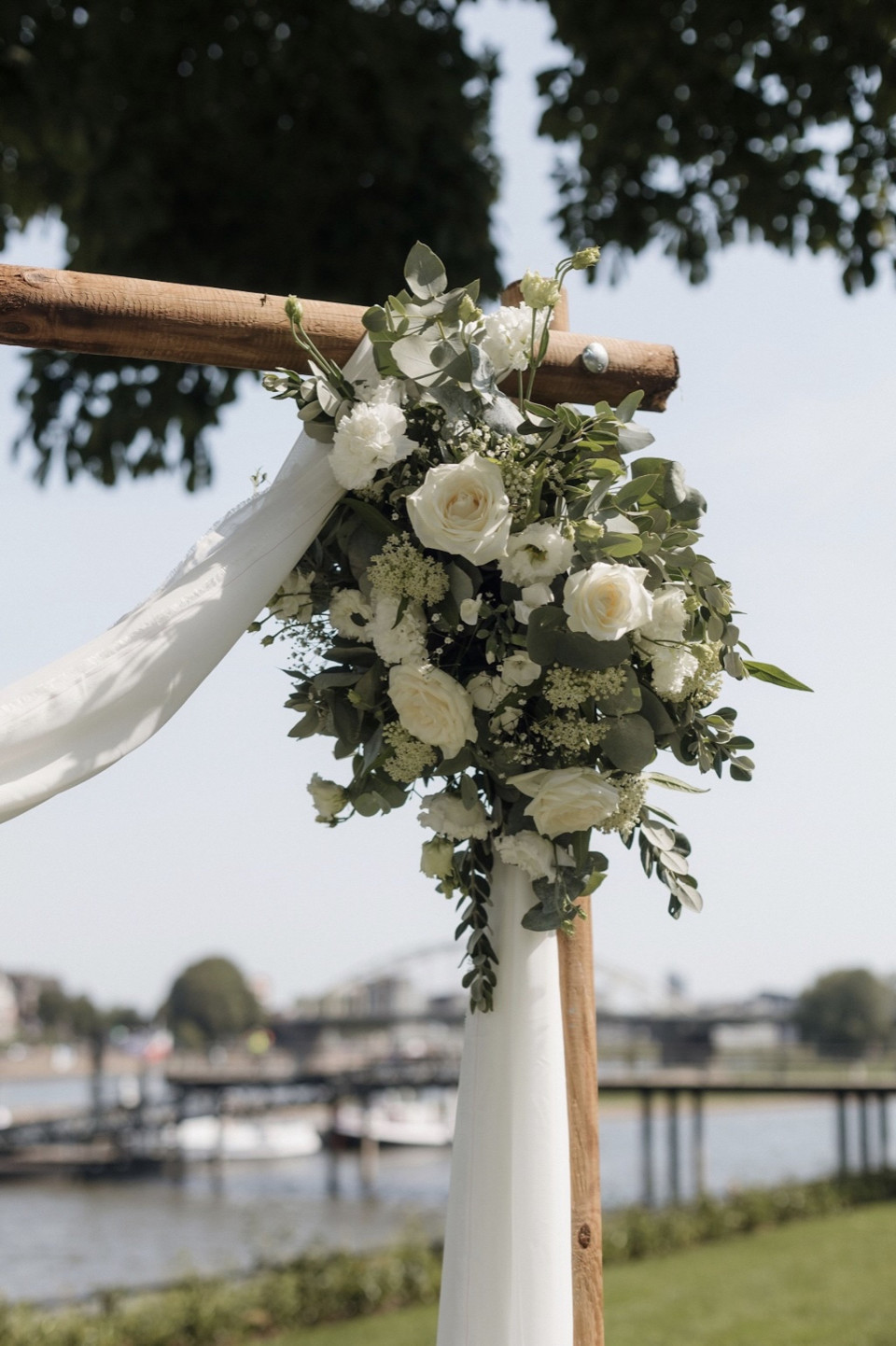 een boeket witte bloemen hangend aan een houten kruis