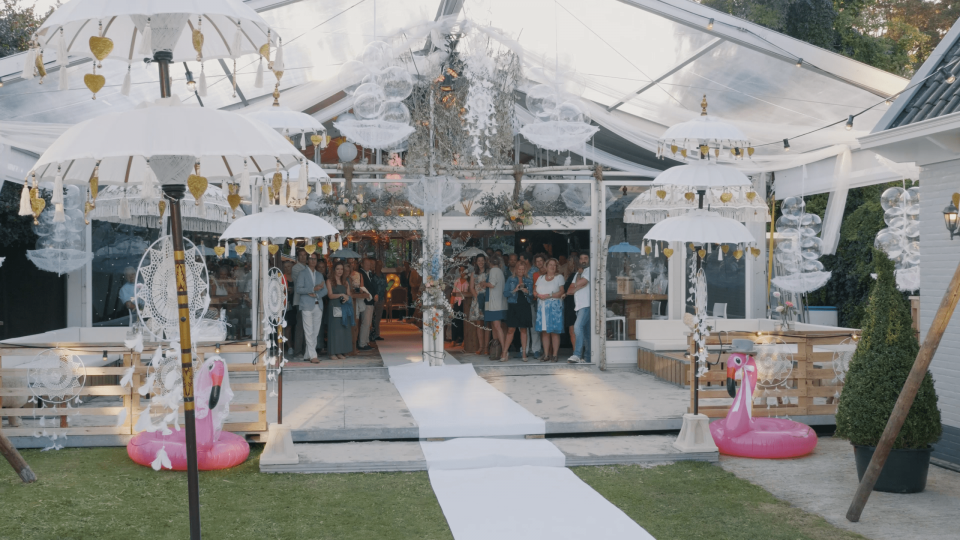 een bruiloftsreceptie met witte parasols en roze flamingo's
