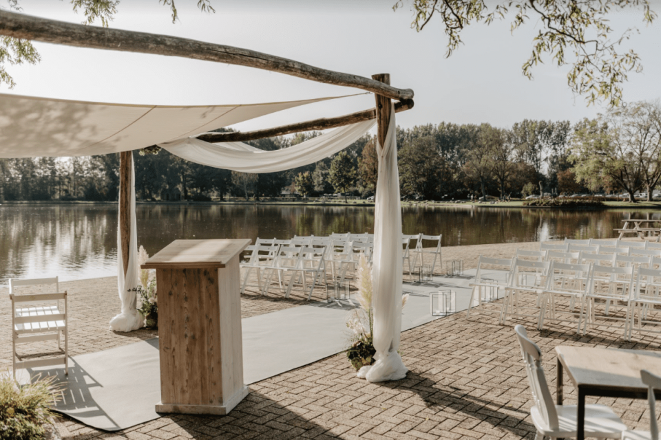 een buiten ceremoniegebied met stoelen en een luifel