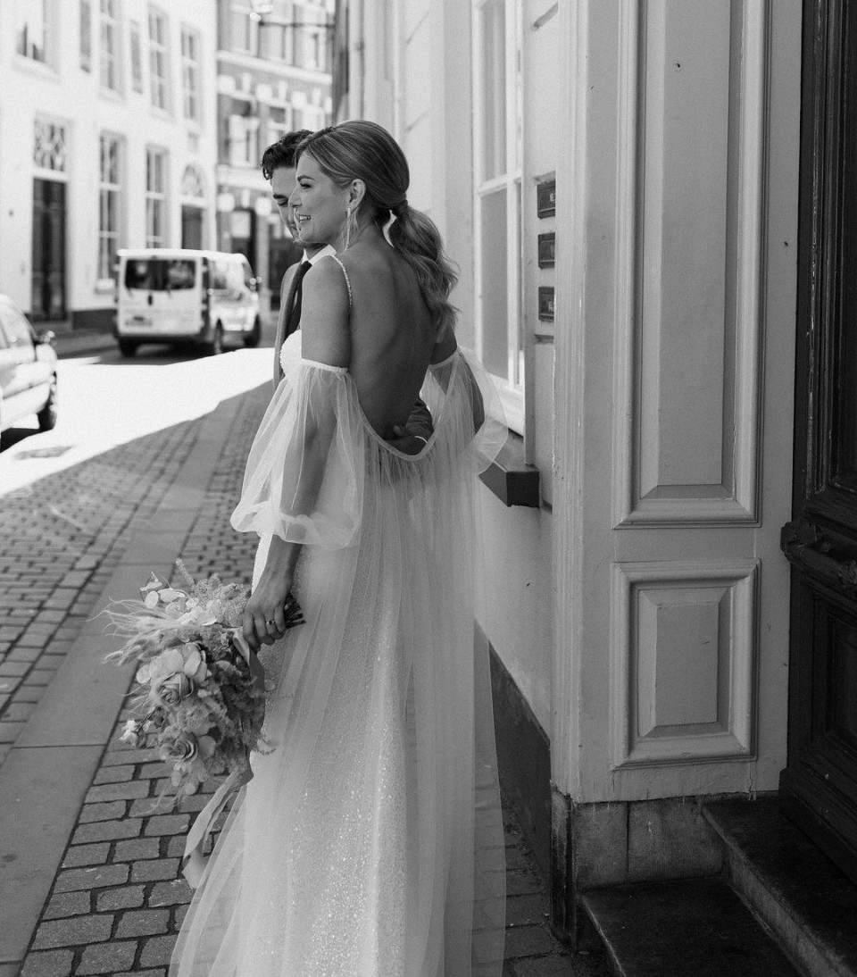 een bruid in een trouwjurk die op straat staat
