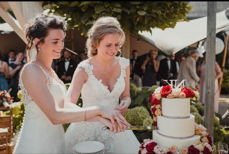 twee vrouwen snijden samen in een bruidstaart