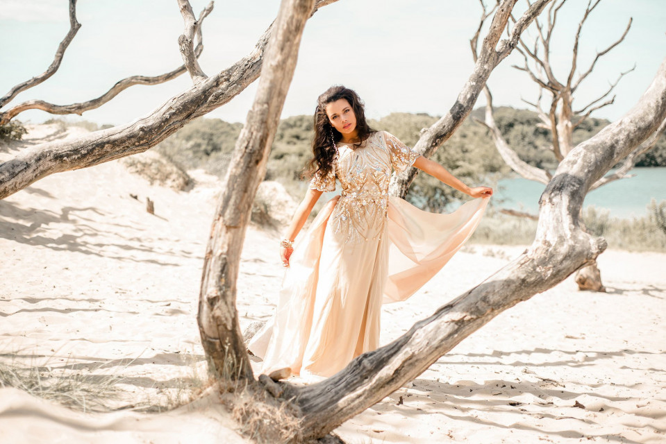 een vrouw in een lange jurk die in het zand staat
