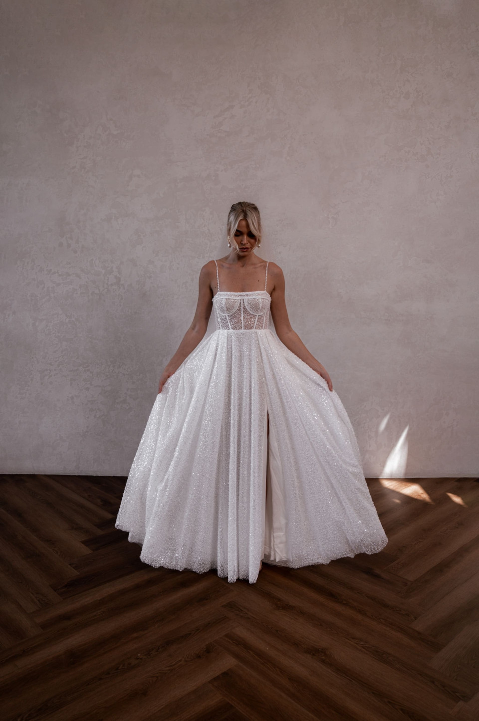 een bruid in een witte trouwjurk staat in een kamer