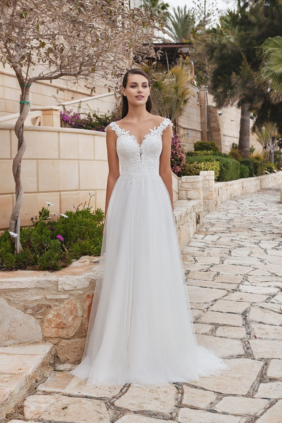 een mooie bruid in een trouwjurk staand op een stenen pad