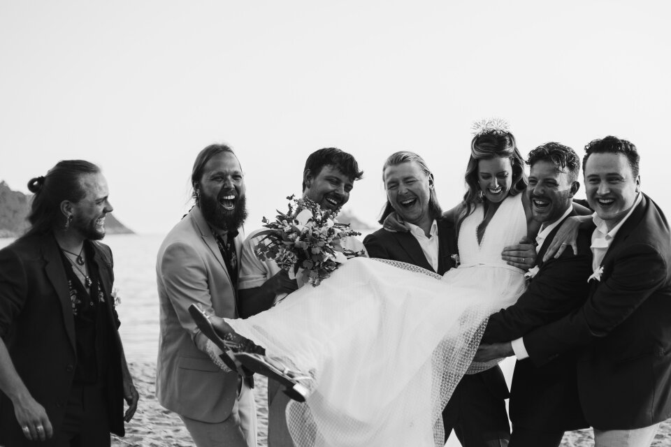 een zwart-wit foto van een bruiloftsfeest op het strand