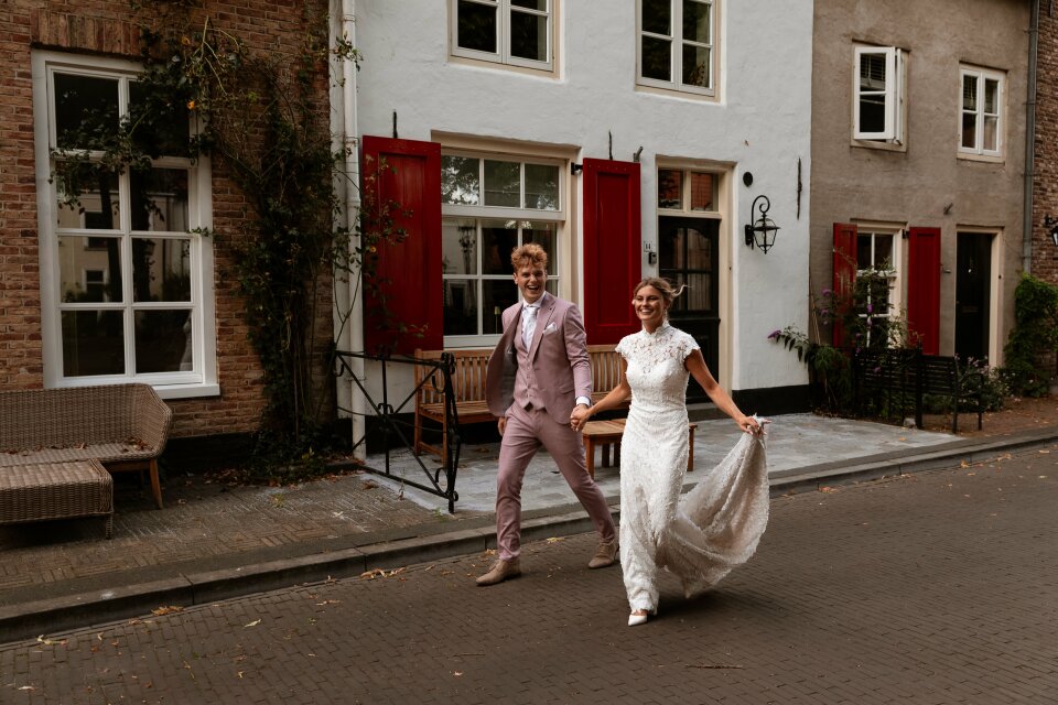 een bruid en bruidegom die de straat aflopen